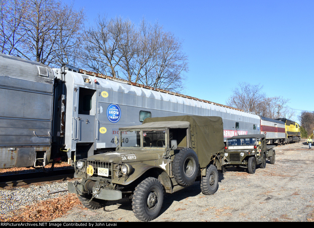 There are a couple of Army colored vehicles resting besides the train along Royal Ave